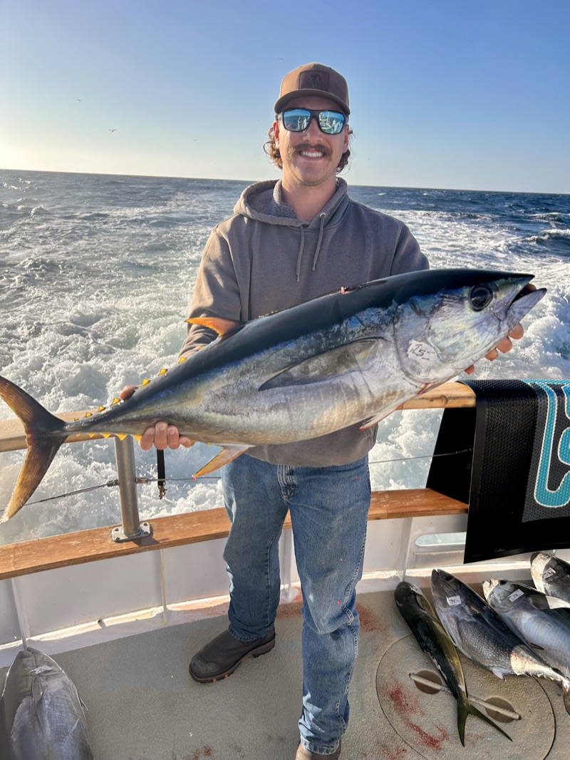 A member holding a tuna aboard the boat on a deep sea fishing trip